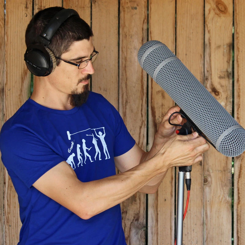 A sound recordist with a mic and a boom operator t-shirt